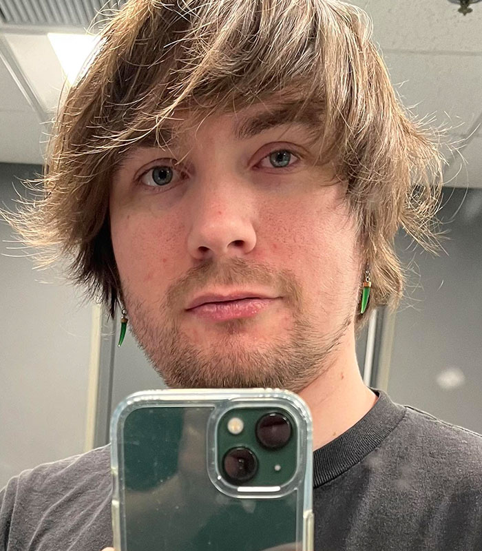 Close-up selfie of a young man with shaggy hair and green earrings, identified as Bryan Kohberger's friend