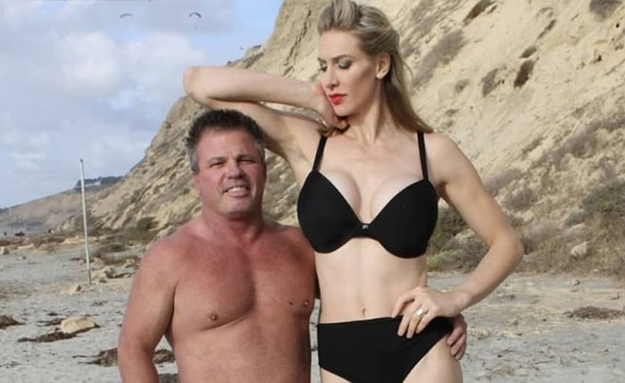 Very tall Domme standing next to a shorter man on a sandy beach. Very tall Domme standing next to a shorter man on a sandy beach.