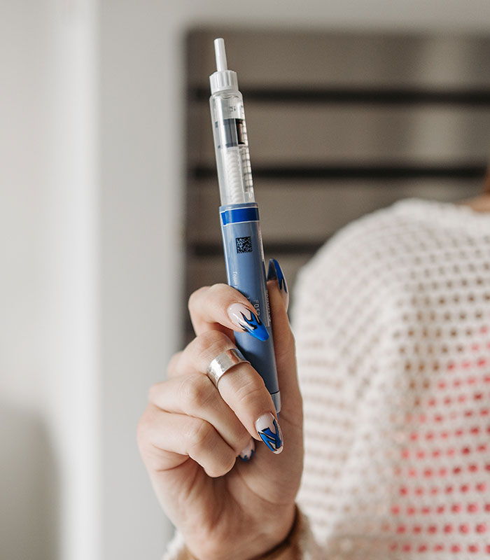 A hand holding a blue weight loss injection pen. A hand holding a blue weight loss injection pen.