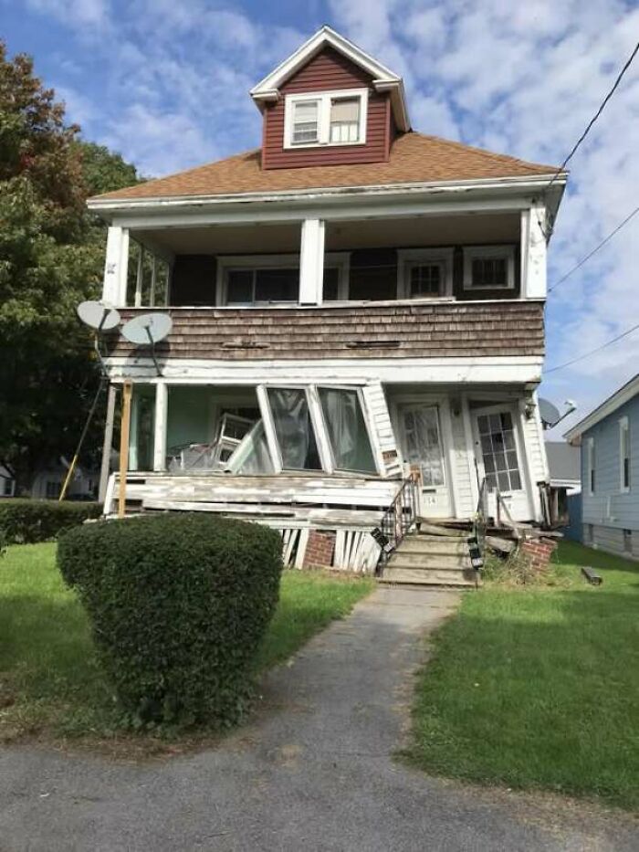 Construction fail showing a severely leaning house with warped windows and doors