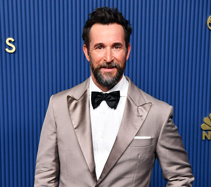 Noah Wyle posing on the red carpet in a tuxedo with a bowtie