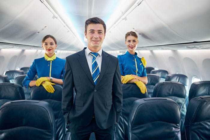 Flight crew standing in an airplane aisle as a flight diverted due to an unruly passenger Flight crew standing in an airplane aisle as a flight diverted due to an unruly passenger