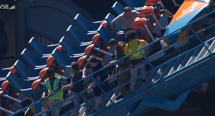 Ride operators assist passengers on a roller coaster incline after a Six Flags accident.