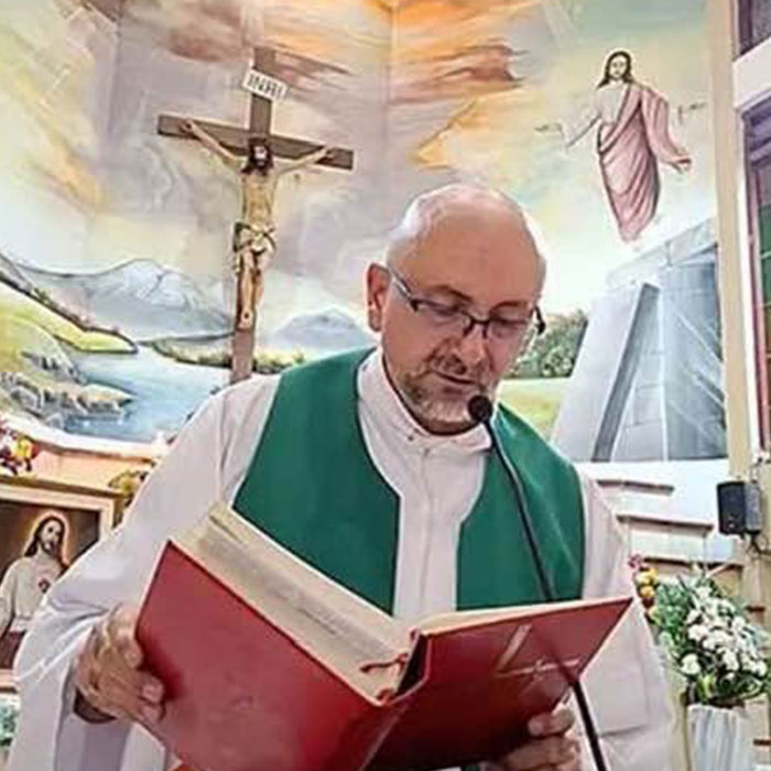 Priest reading from red book in church with crucifix behind Priest reading from red book in church with crucifix behind