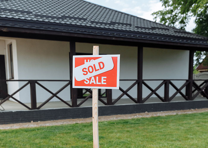 Sold sign in front of a house, representing passengers who sold homes for a permanent cruise.