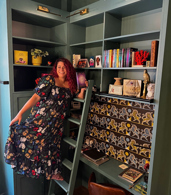 Bestselling author posing on a ladder inside a home library filled with books