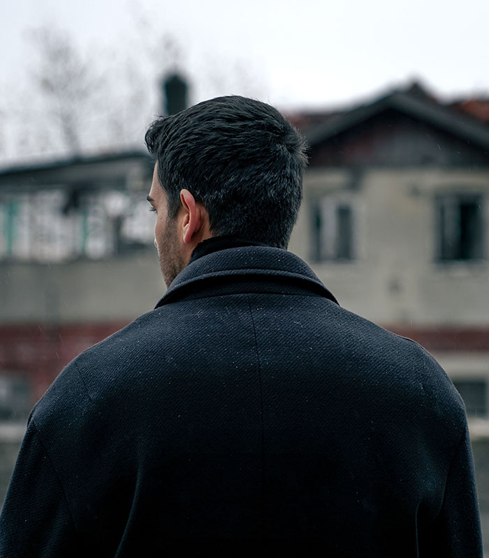 The back of a man looking at a building, symbolizing an ex-husband reflecting on marriage sacrifices