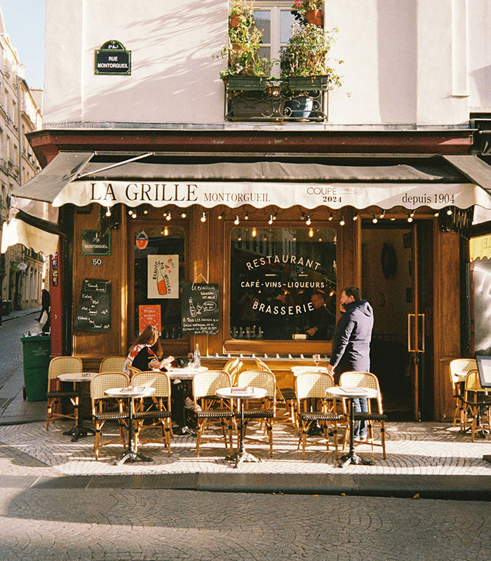 Exterior view of a classic French brasserie with outdoor seating, where a server might encounter customers. Exterior view of a classic French brasserie with outdoor seating, where a server might encounter customers.