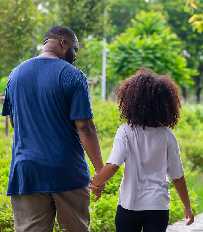 A father walking hand in hand with his young daughter, highlighting a caring bond with dad.