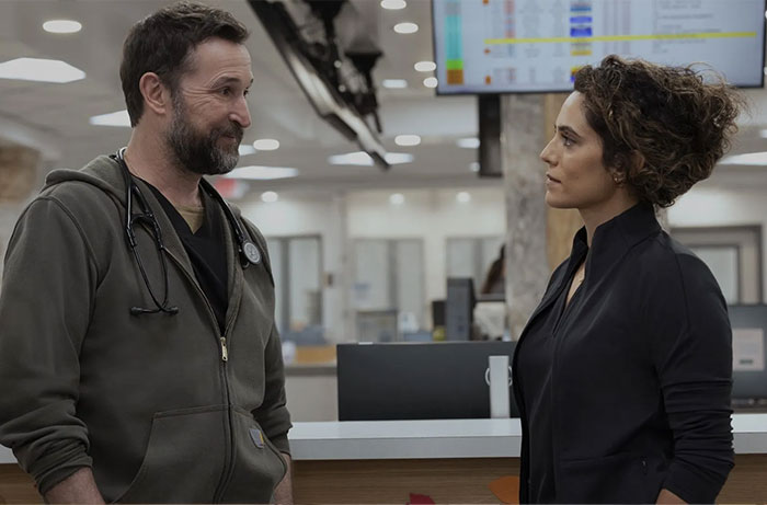Noah Wyle talking to a female colleague in a hospital setting