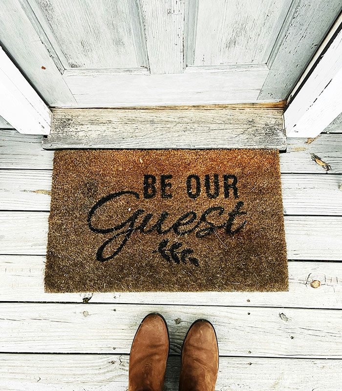 Be Our Guest doormat at the entrance of a vacation house, referencing an Airbnb host welcoming guests.