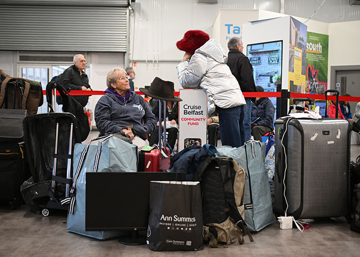 Passengers wait with luggage at a terminal for their permanent cruise ship.