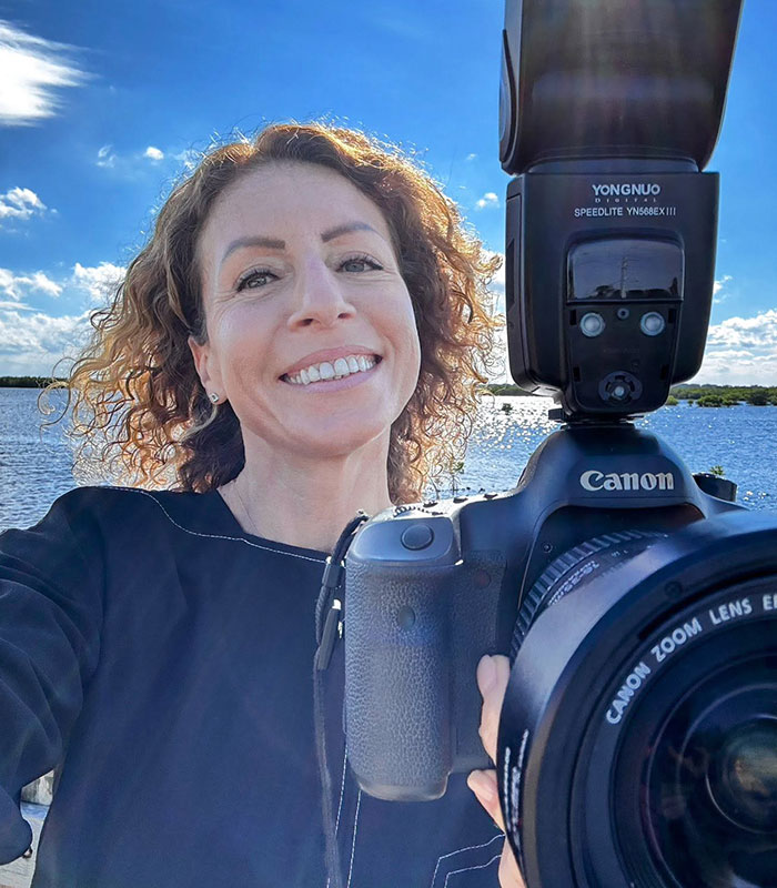 Mom who left kids home alone smiling while holding a professional camera outdoors