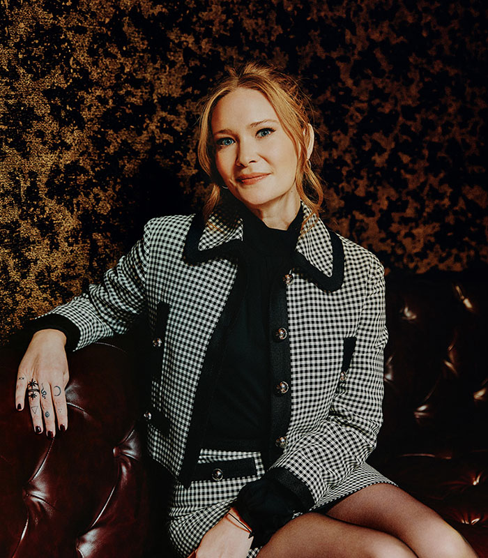 A bestselling author posing in a plaid jacket, representing the draw of the romantasy obsession.