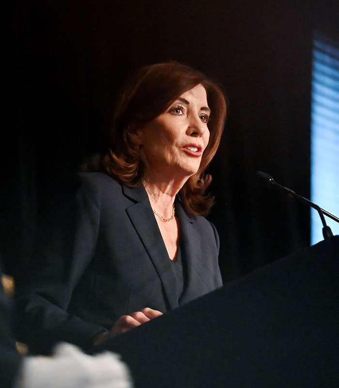 A woman speaking at a podium regarding the Cornell 7 scandal.