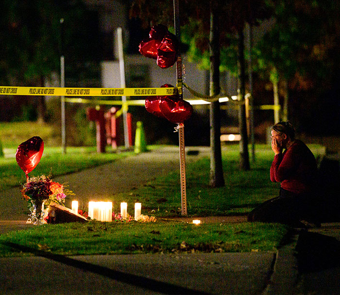 Mourner kneeling at a candle memorial for Oregon elementary school tragedy