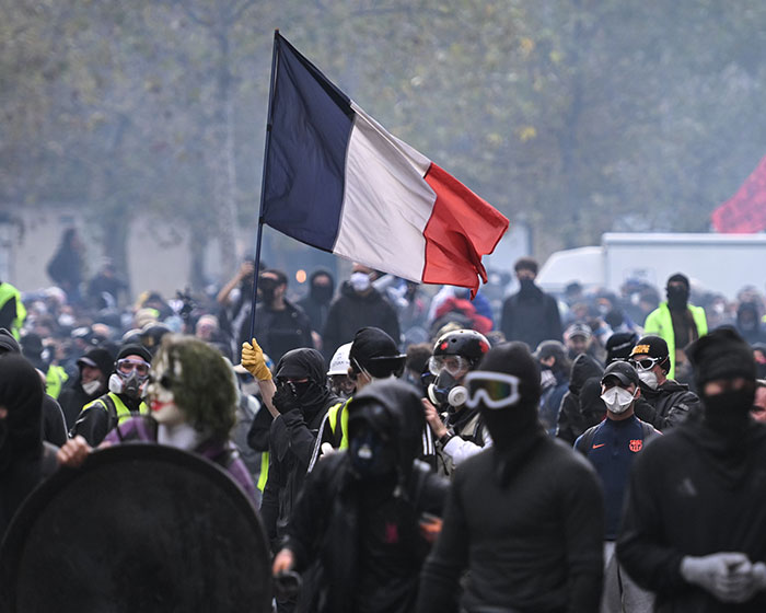 Protesters marching in the street holding a French flag during the France riots