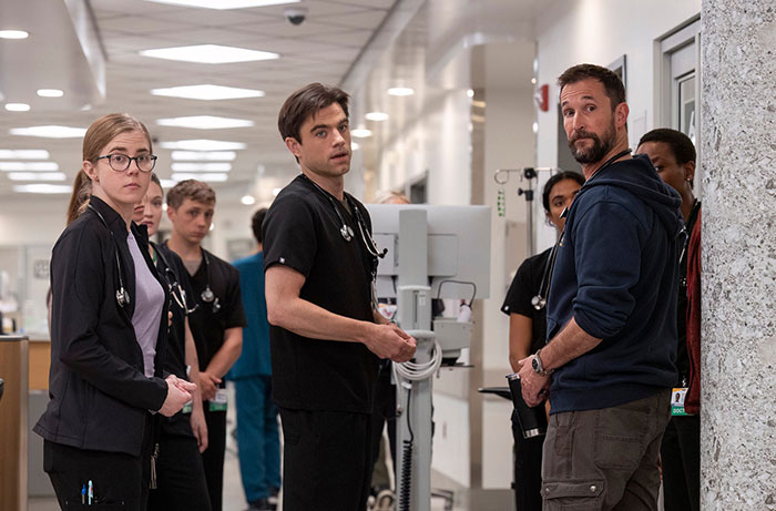 Noah Wyle standing with hospital staff in a medical drama scene