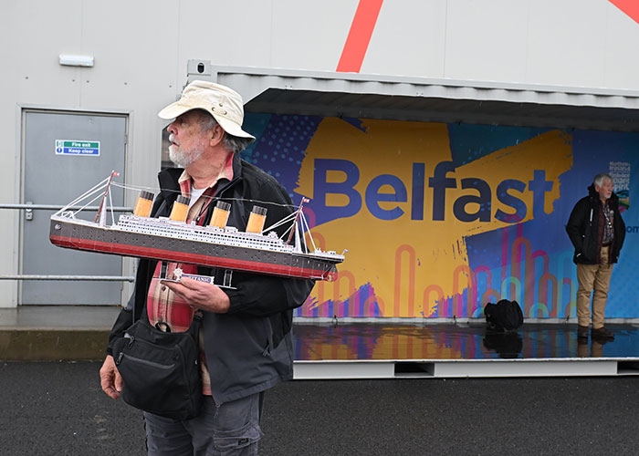 A passenger holding a toy ship model while waiting for a permanent cruise in Belfast.
