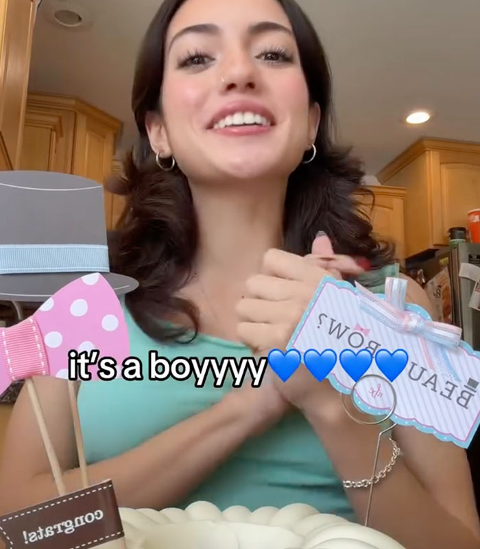 A woman smiling while holding gender reveal props during a special announcement. A woman smiling while holding gender reveal props during a special announcement.