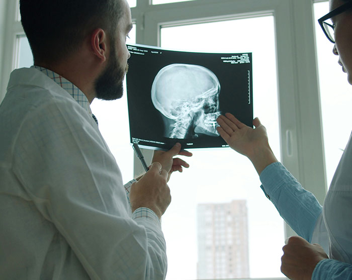 Two doctors analyzing a head and neck X-ray film as medical experts sound the alarm on health risks. Two doctors analyzing a head and neck X-ray film as medical experts sound the alarm on health risks.