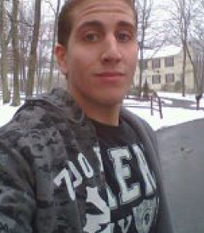 A young Bryan Kohberger posing outdoors in a camouflage jacket with a snowy background