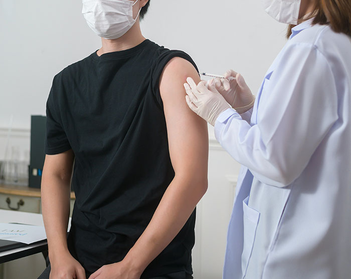 A healthcare worker administering a vaccine to a patient's arm to help prevent illness and cancer risks. A healthcare worker administering a vaccine to a patient's arm to help prevent illness and cancer risks.