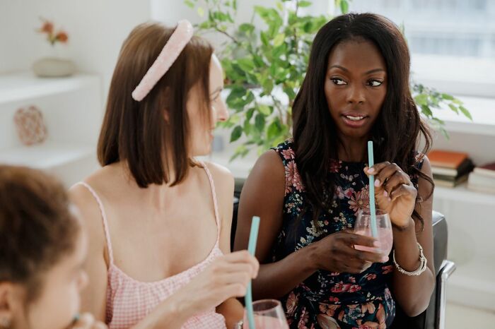 Two women talking and drinking smoothies indoors