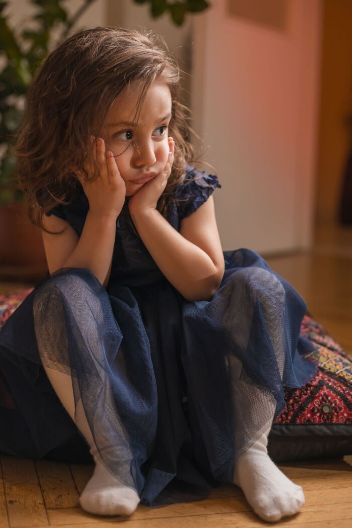 A sad young girl resting her head on her hands, showing the emotional impact of choosing divorce.