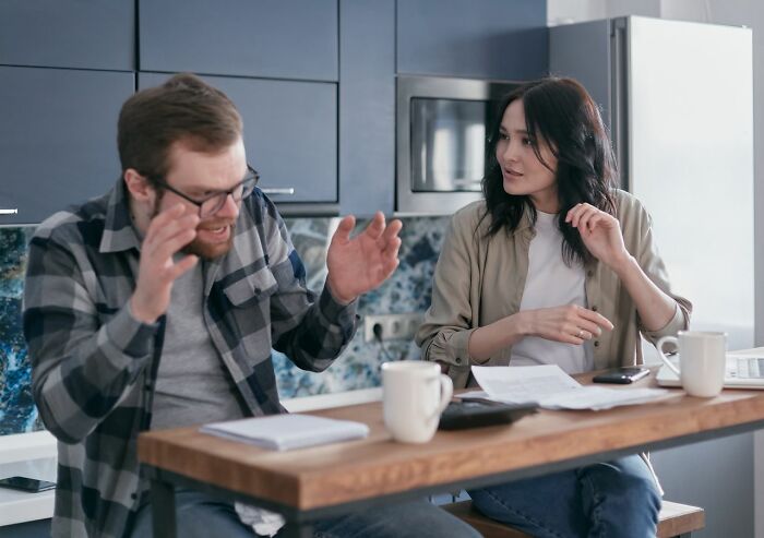 Couple arguing about seriously disturbing things at kitchen table with papers and coffee