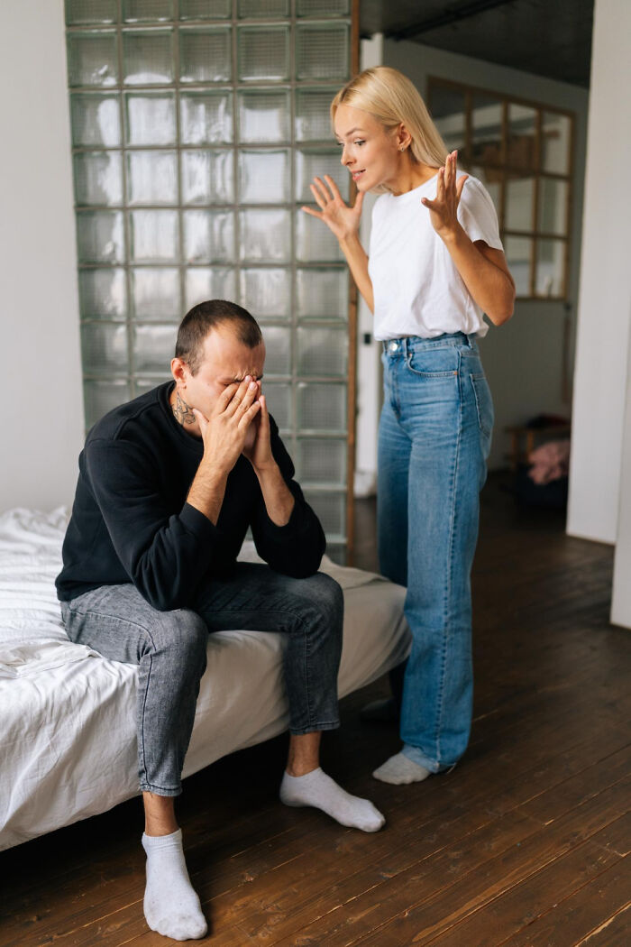 A woman arguing with a man sitting on the bed with his face in his hands, facing marriage conflict.