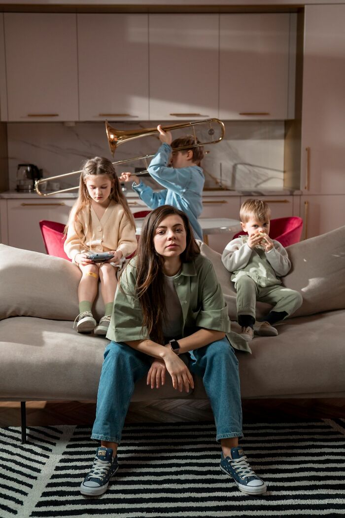 Stressed mother sitting on couch with noisy children in background