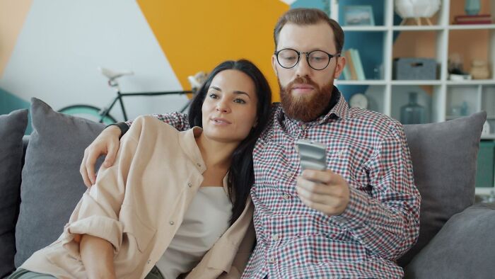 A couple sitting together on a couch, illustrating a distant relationship leading to divorce.