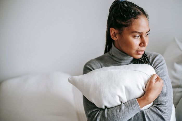 A worried woman hugging a pillow tightly while facing relationship issues and divorce