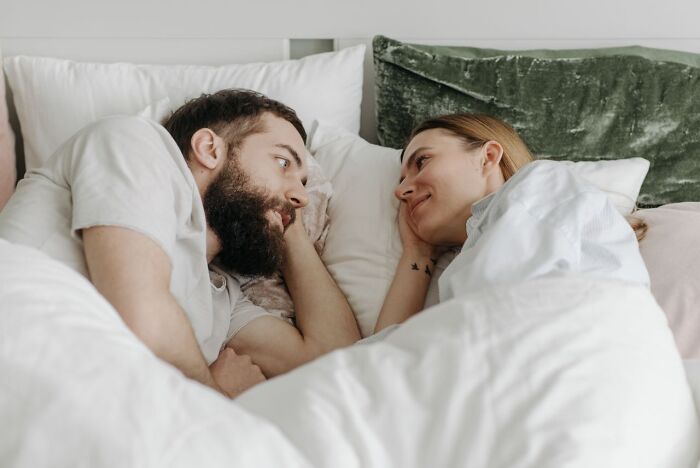 A couple lying in bed looking at each other, representing relationship crossroads and divorce.