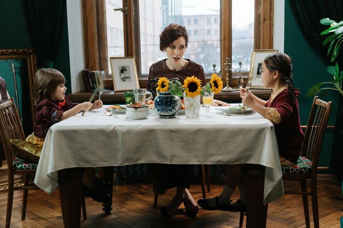 Family having dinner with sunflowers on table during serious disturbing conversation