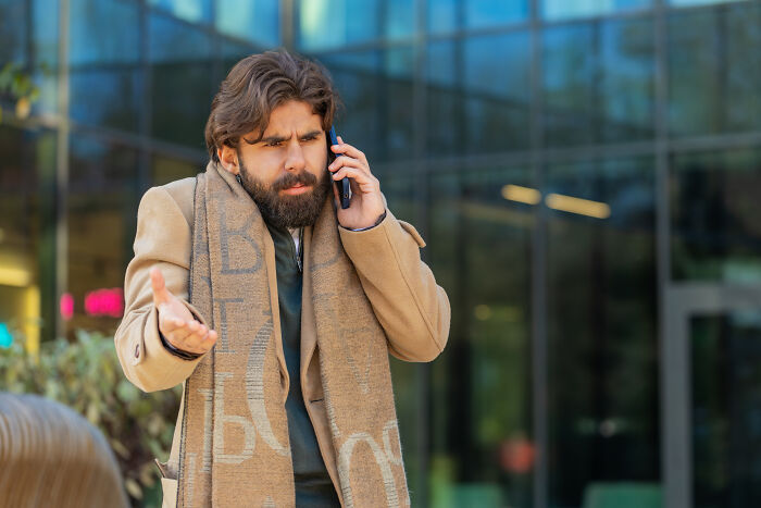 A frustrated man talking on his phone outdoors, contemplating divorce over staying together.