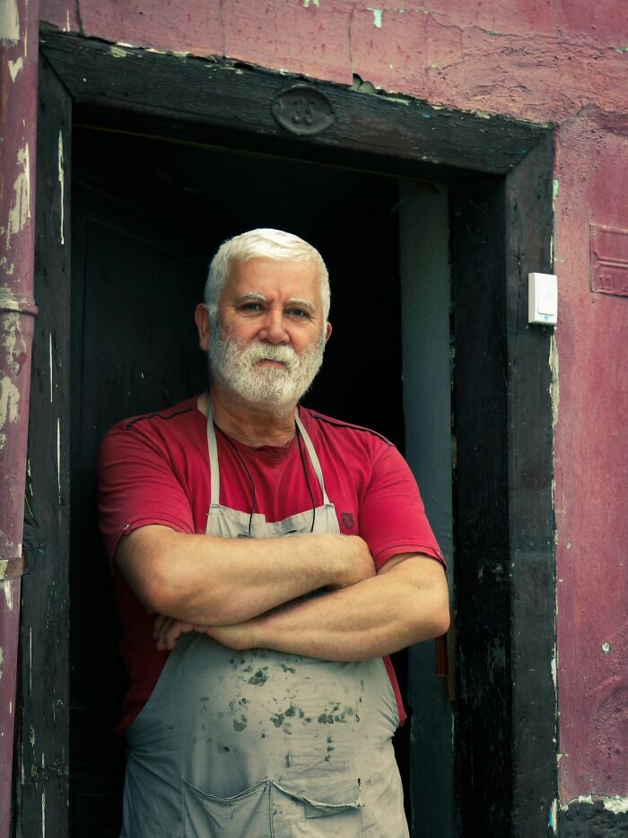 Confident older man in apron standing at rustic doorway