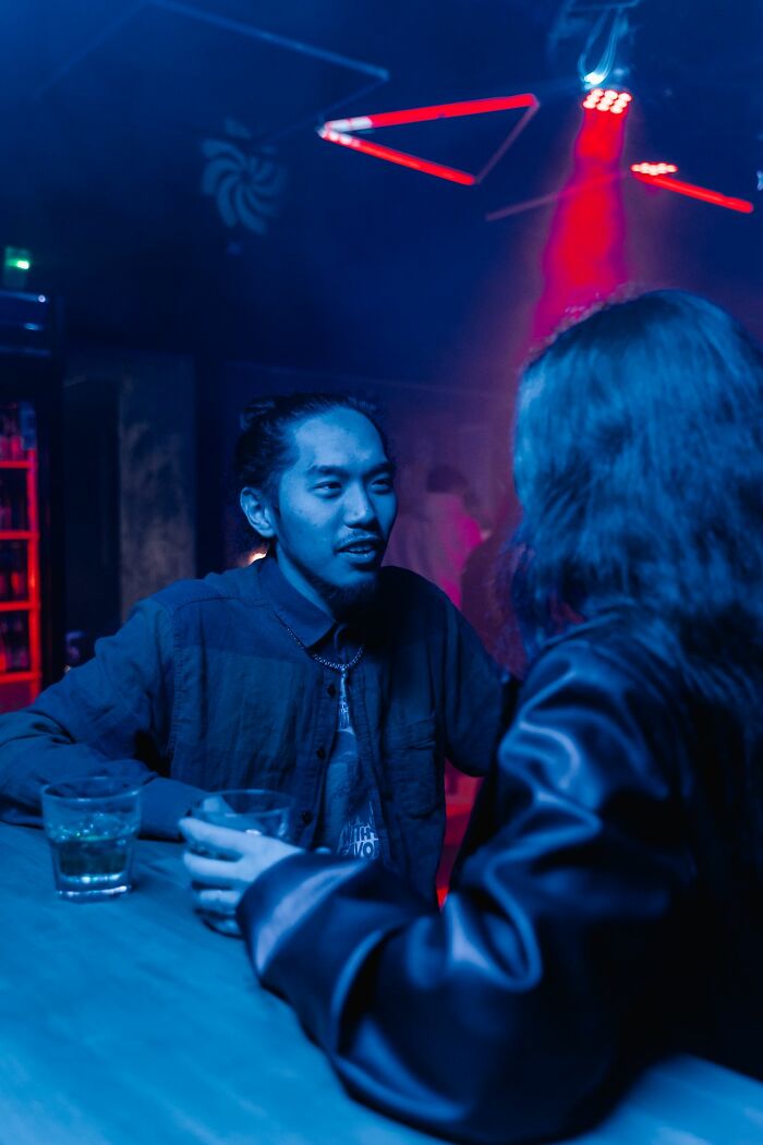 People talking at dimly lit bar sharing seriously disturbing admissions