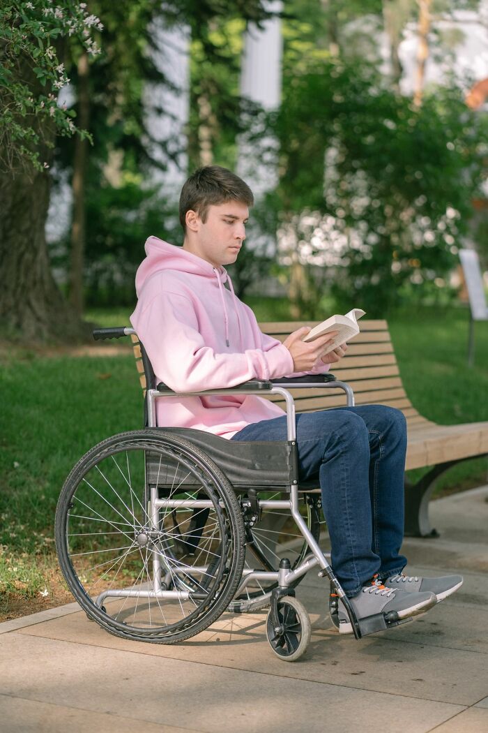 Man in wheelchair reading book outdoors, reflecting on disturbing admissions