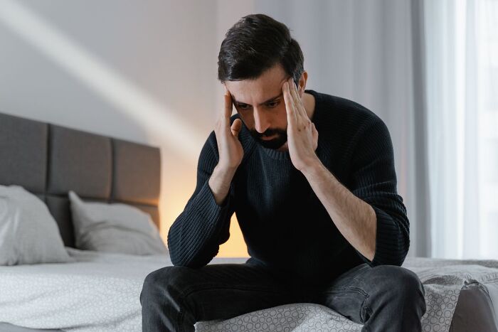 A stressed man holding his head in his hands thinking about divorce