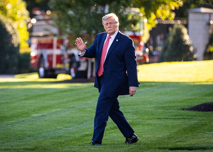 Donald Trump waving as he walks across a grassy lawn. Donald Trump waving as he walks across a grassy lawn.