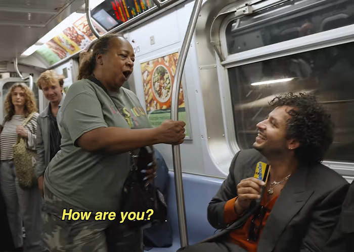 A woman talks to a host holding a card during a subway interview. A woman talks to a host holding a card during a subway interview.