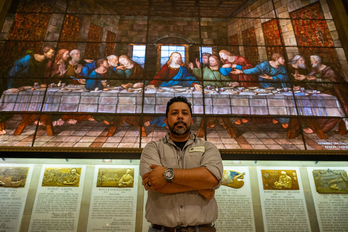 Stained-glass expert standing in front of a large Last Supper stained-glass artwork Stained-glass expert standing in front of a large Last Supper stained-glass artwork