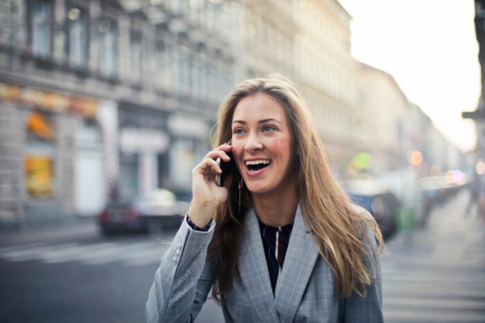 A happy woman talking on the phone outdoors, representing a woman who got a life-changing inheritance. A happy woman talking on the phone outdoors, representing a woman who got a life-changing inheritance.