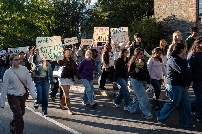 Students marching in protest with signs demanding justice during the Cornell 7 scandal.