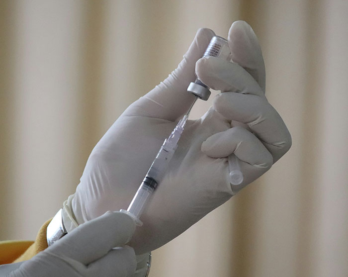 Gloved hands preparing a syringe for a vaccine, illustrating cancer rates prevention. Gloved hands preparing a syringe for a vaccine, illustrating cancer rates prevention.