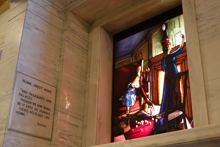 Stained glass depicting a family scene with children and adults inside a home Stained glass depicting a family scene with children and adults inside a home