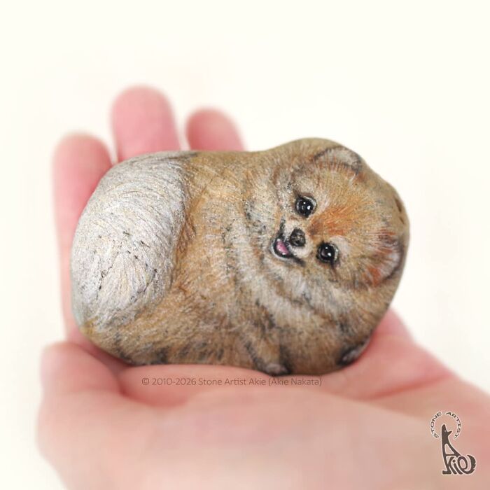 Japanese artist hand holds stone with realistic dog painting