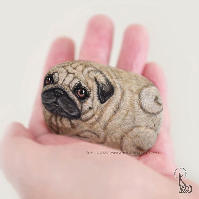 Stone art featuring a lifelike pug dog held in palm